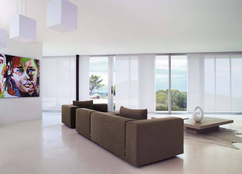 diaz paneelgordijnen witte paneelgordijnen interieur met bruine zetel en kleurijk kunstwerk 1115x800 1